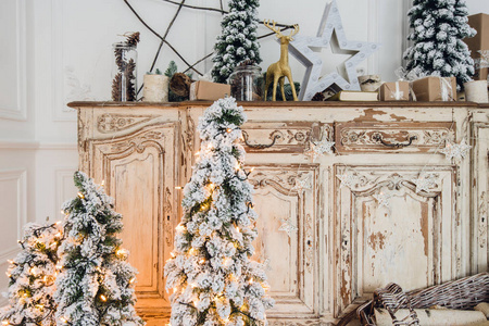 木制抽屉柜的圣诞树在白色室内, 装饰着人工花, 花环和玩具