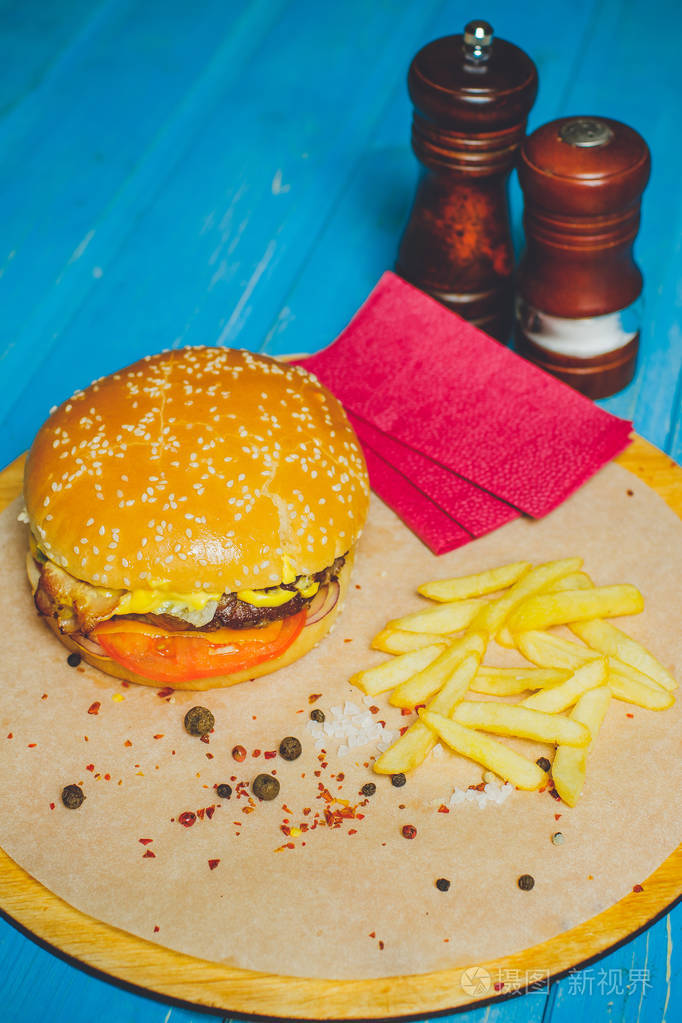 新鲜牛肉汉堡加奶酪蔬菜和辣番茄酱纸蓝木底