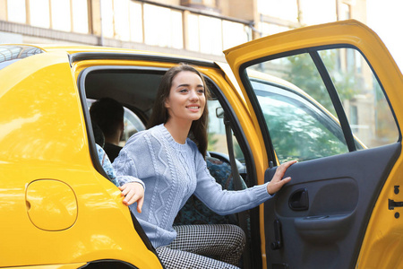 年轻妇女从出租汽车下车照片