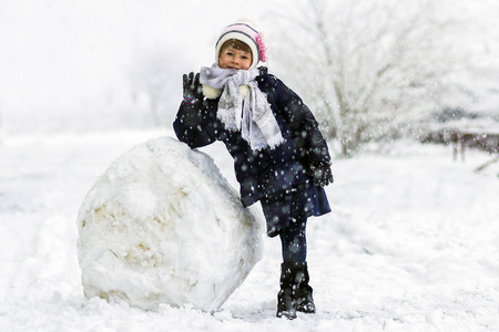 冬季户外小女孩在大雪球附近图片