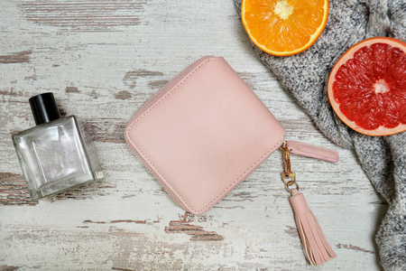 小粉红色的女性钱包, 香水和柑橘的木制背景。时尚理念