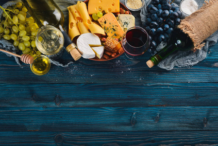 蓝色木桌上有各种奶酪葡萄酒蜂蜜坚果和香料。上景。免费的文本空间。