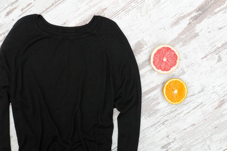 黑色毛衣的木制背景, 一半的柑橘。时尚理念