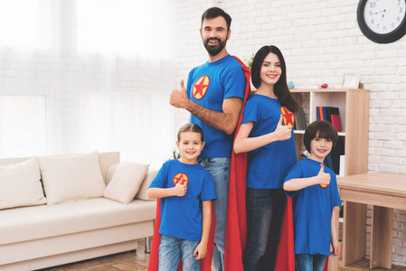 年轻的家庭在红色和蓝色的超级英雄的西装。他们的面孔在面具和他们在雨衣