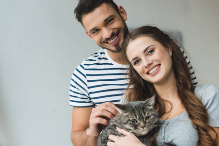 微笑的年轻夫妇手里拿着猫，看着镜头