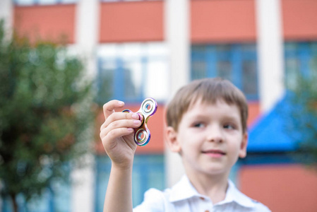 可爱的小男孩玩摆弄手微调框在夏季的一天。流行和时尚的玩具，儿童和成人
