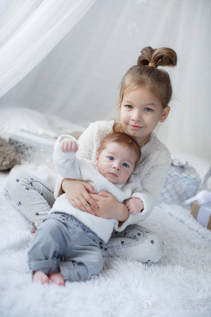 小女孩和男婴兄妹在父母床上玩耍.