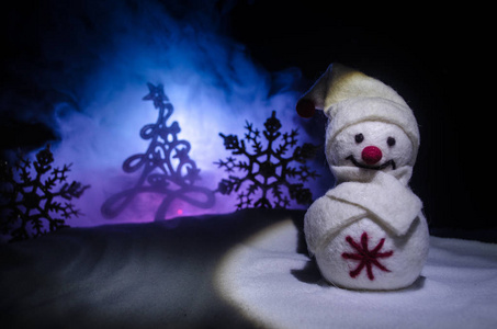 新年。雪人为新年卸礼物。白色的雪人在傍晚的背景下被圣诞树包围。玩具装饰