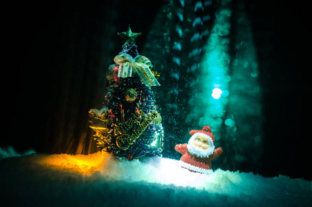 圣诞快乐圣诞老人娃娃在圣诞树和雪的时间。丰富多彩的散背景。圣诞老人和圣诞快乐模型图玩具在黑暗的色调