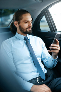 年轻的成功男子在手机上工作坐在汽车