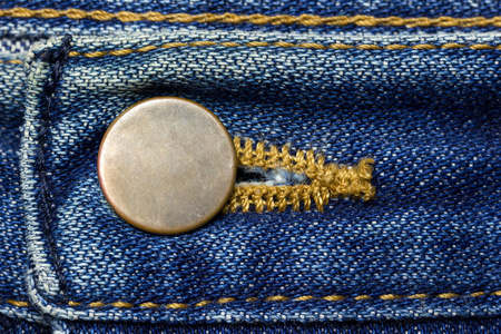 老式蓝色牛仔裤的黄铜纽扣。 适合背景文章的时尚服装。