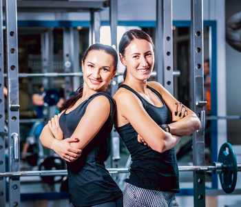 两个爱运动的微笑女人在健身房。