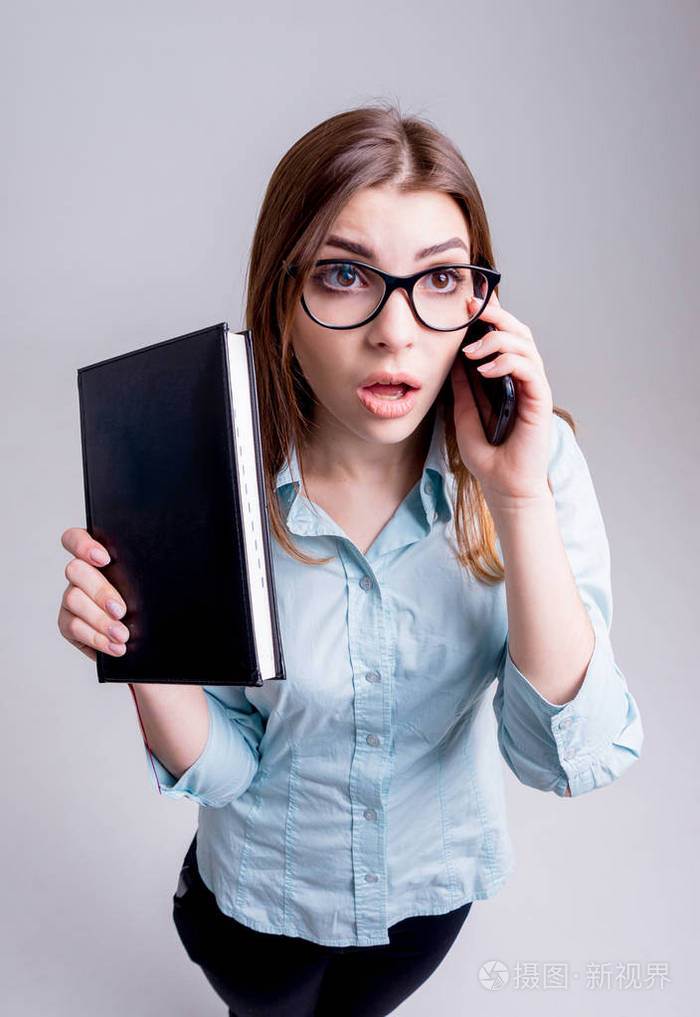 办公室里戴眼镜的年轻女商人,在灰墙前照片-正版商用图片10evd2-摄图