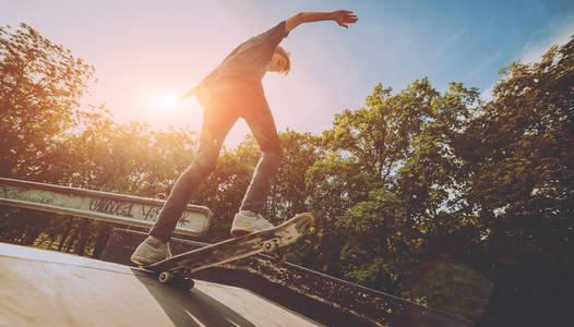 年轻的滑板运动员在滑板公园玩花样。