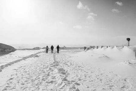 在寒冷的冬天冰岛在白色雪有3人在温暖的衣裳