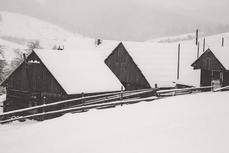 村庄的全景在冬天的山上覆盖着雪。 冬季景观。 自由和孤独的概念。