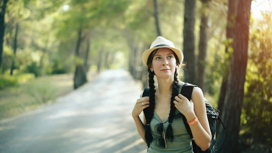 有吸引力的旅游女孩微笑着，看着相机在行走和美丽的森林徒步旅行时的画像