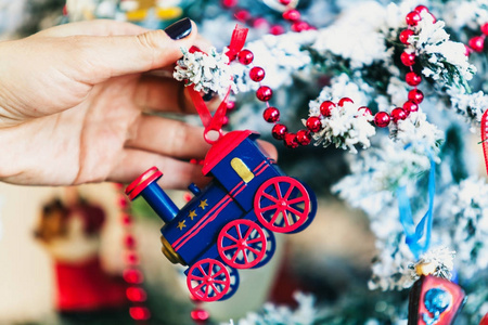 妇女的手挂在圣诞树玩具蓝色机车