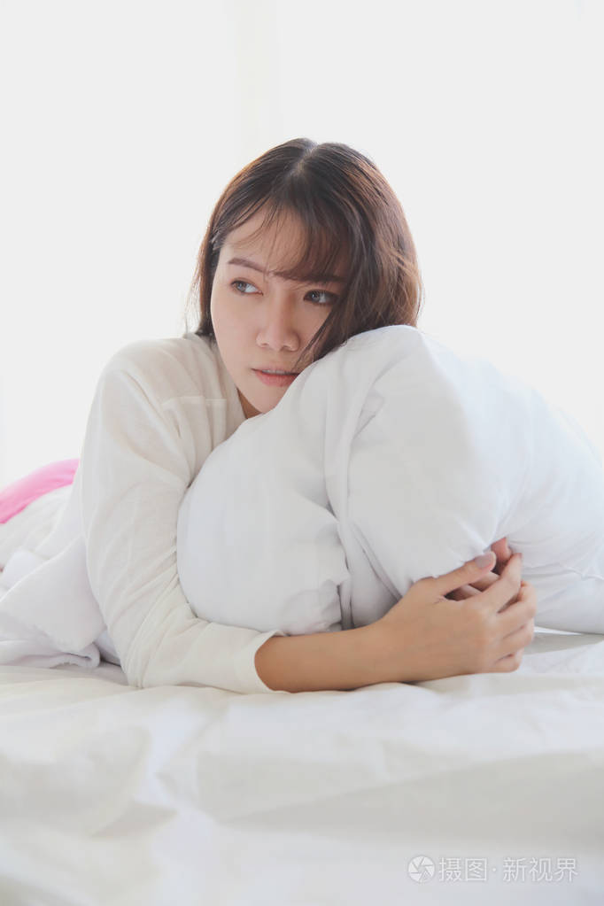 亚洲年轻女子在床上醒来时,语气是白色的
