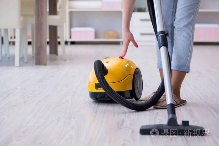 在家做清洁的妇女用真空吸尘器