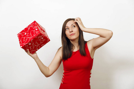 有兴趣和订婚的年轻女子身着红色礼服和圣诞帽举行礼品盒, 认为她是在白色背景。礼物被隔绝的圣诞老人女孩。新年假期2018概念