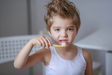 滑稽的小男孩拿着牙刷和刷牙的画像