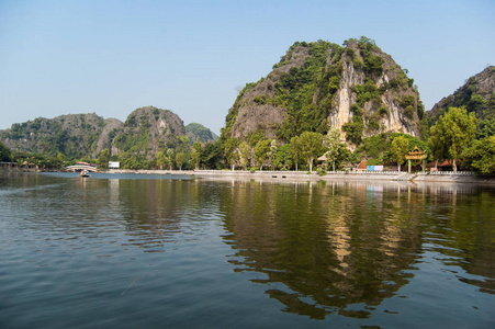 NgoDong河上岩石背景上的房屋和船只。 船站在岸边等待乘客。 越南一个古镇。