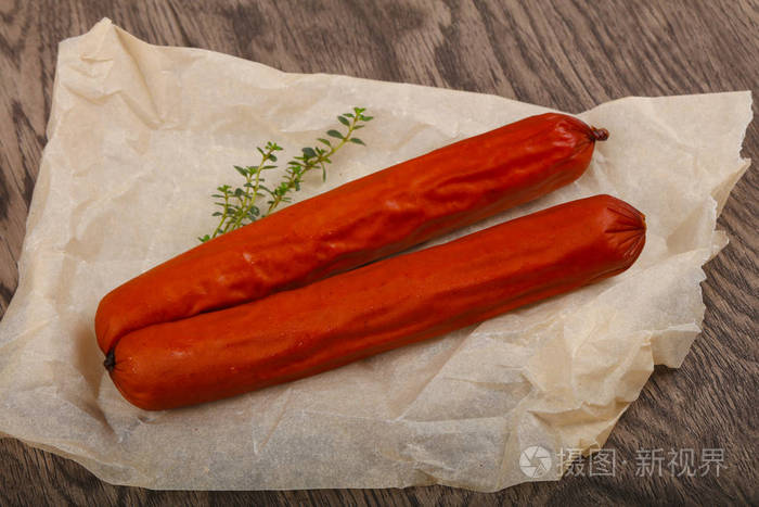 两根带百里香叶的香肠在木制背景下准备吃