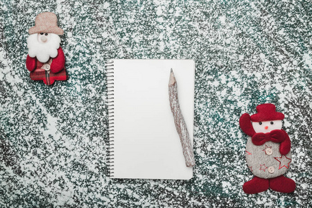 上面的顶部视图从上面的记事本木制老式笔和手工圣诞老人和雪人玩具在灰色大理石背景上，有空间写文字问候。
