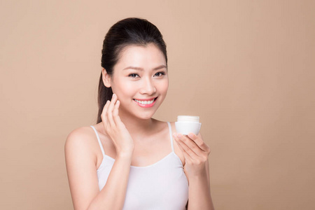 护肤品。 美丽的亚洲女人展示保湿剂或乳液产品。