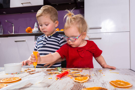 可爱的小男孩和女孩双胞胎在厨房里装饰圣诞饼干