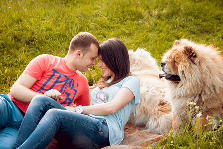 年轻夫妇带着他们的狗，在公园里散步，玩得很开心