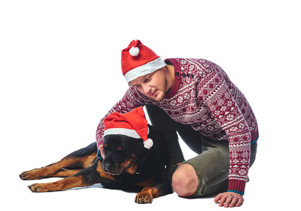 一个穿着羊毛衫和圣诞老人帽的人，他的狗被隔离在白色上。