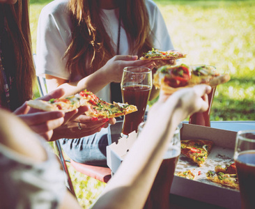 快乐的朋友在公园野餐吃披萨。