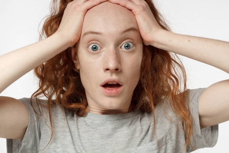 特写肖像的情绪红发女孩孤立的灰色背景与强烈的恐惧表情, 圆眼睛