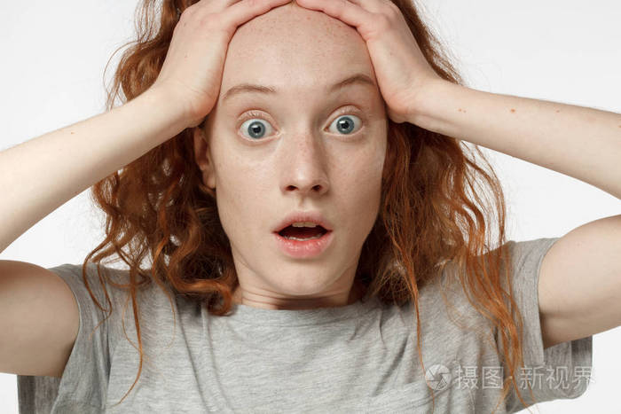 特写肖像的情绪红发女孩孤立的灰色背景与强烈的恐惧表情, 圆眼睛