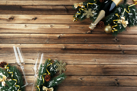 棕色木桌上有玻璃和杉树枝的香槟酒瓶