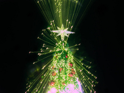 缩放人工松树圣诞树的爆裂光，星星在LED装饰灯的顶部，离焦背景，并为平安夜新年聚会节日和庆祝活动提供纹理