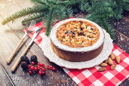 自制圣诞或新年假期浆果馅饼与坚果在木桌背景。节日甜点的概念
