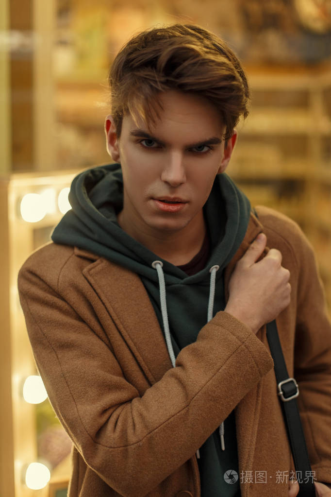 在街上穿着时髦上衣的年轻小伙子的时尚肖像