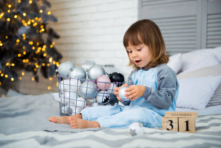 小可爱的小女孩是2岁坐在靠近圣诞树和看日历。12月31日