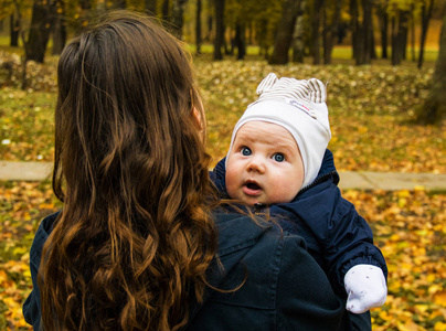 年轻的母亲和你的小儿子在秋季公园。有趣的和