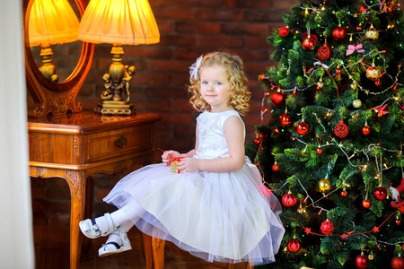 美丽的小我是一个穿着节日礼服的女孩，坐在椅子上，手里拿着礼物，背景是一篇喜庆的圣诞论文