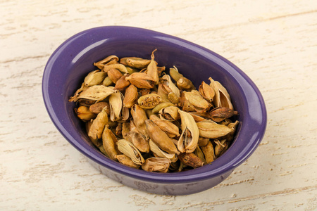 干燥的豆蔻种子堆在碗里的木制背景上