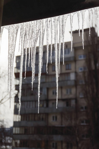 危险的冰柱悬挂在房子的白雪皑皑的屋顶上。大 ici