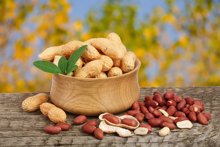 老醋花生与叶上老与模糊的花园背景木制的桌子上的碗中的花生照片