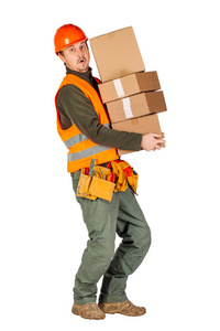男建筑工人或手工工人在头盔持有一堆纸板箱在白色墙壁背景。 建筑维修人员及维修概念