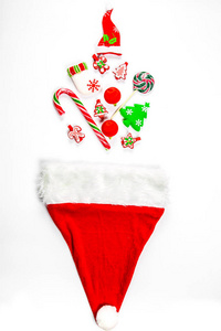 圣诞背景与圣诞老人的帽子, 其中散落的礼物, 糖果, 新年装饰品的白色背景玩具。广告, 购物, 折扣和冬季假期的礼物的概念