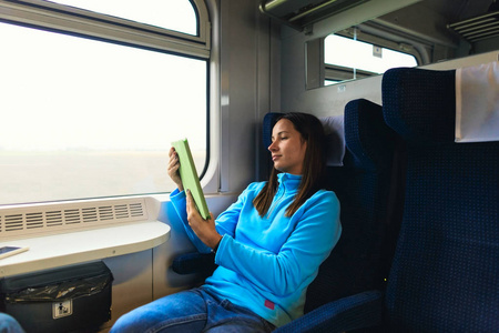 旅途愉快。坐着平板电脑坐在窗边坐火车的女人