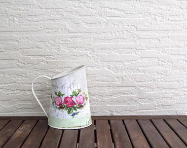 白色的水壶茶杯，上面放着红色的玫瑰花，放在一张棕色的木桌上，放在白色的墙上，背景模板上，供文字使用